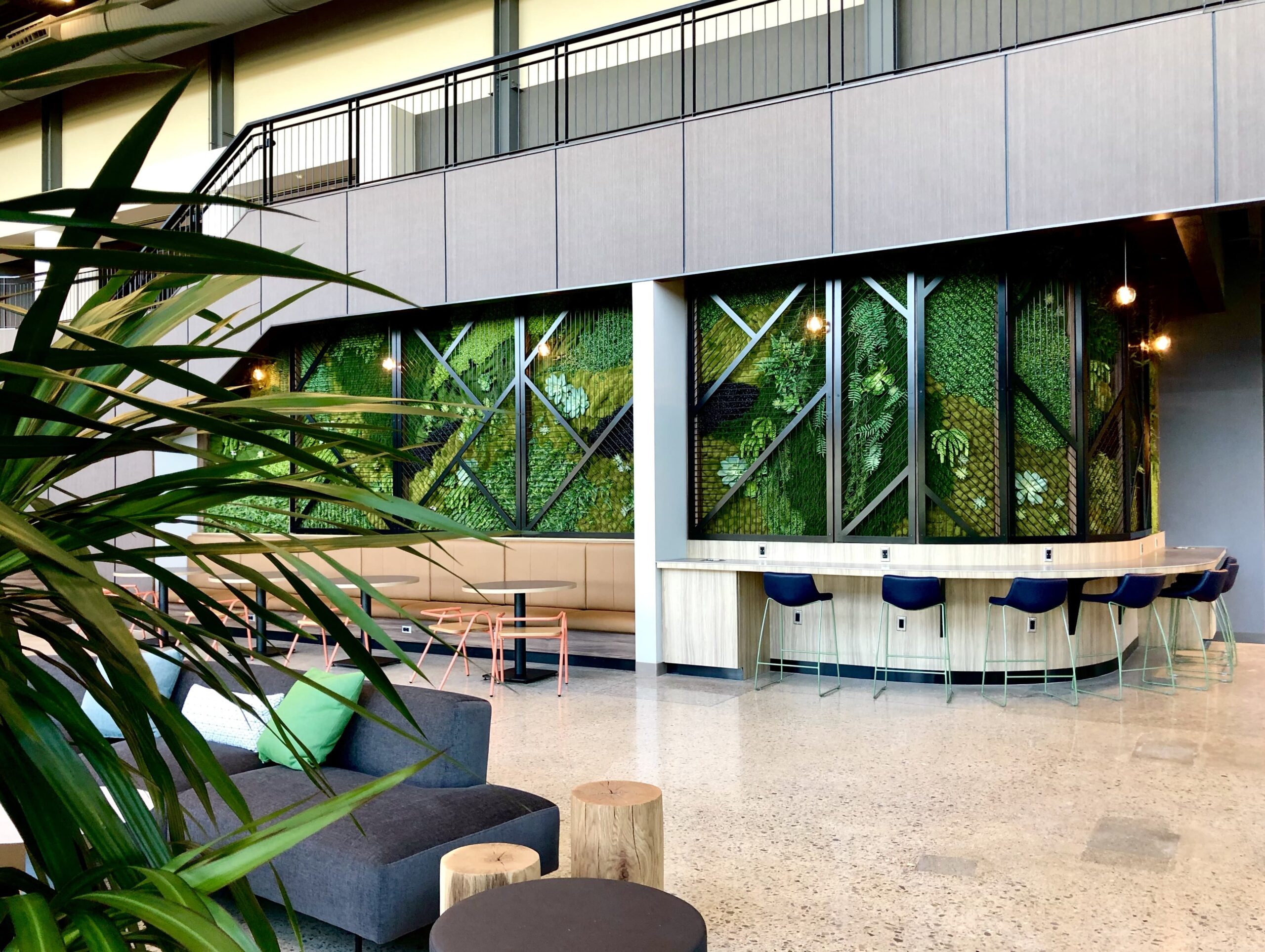 Modern office lounge with bar seating and a large green wall.