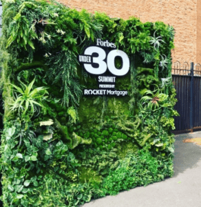 Portable artificial green wall display with dense foliage used for an event backdrop.