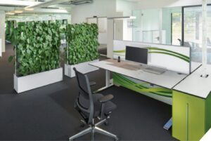 Modern office workstation with green accents and a plant wall divider.