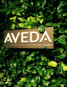 AVEDA logo displayed on a lush green living wall with dense foliage.